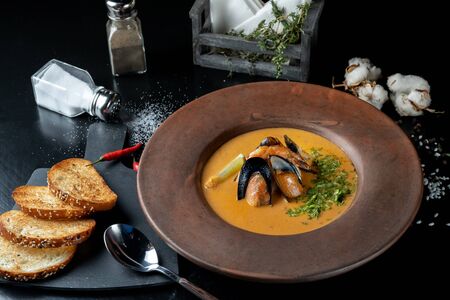 Spicy soup of mashed potatoes with mussels from the pumpkin with greens. Beautifully served table.の写真素材