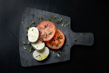Tomato and mozzarella with basil leaves on a black slate.の写真素材