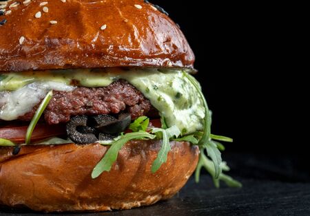 Burger with olives, tomatoes, herbs and pesto.の写真素材