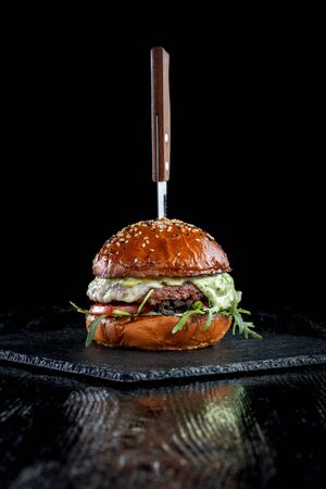 Burger with olives, tomatoes, herbs and pesto.の写真素材