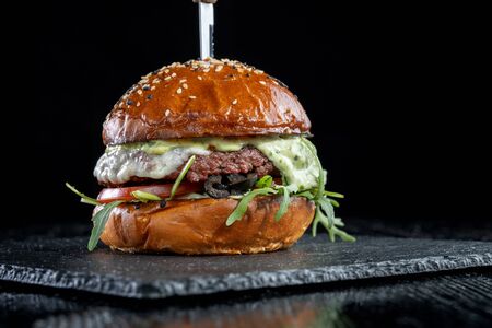 Burger with olives, tomatoes, herbs and pesto.の写真素材