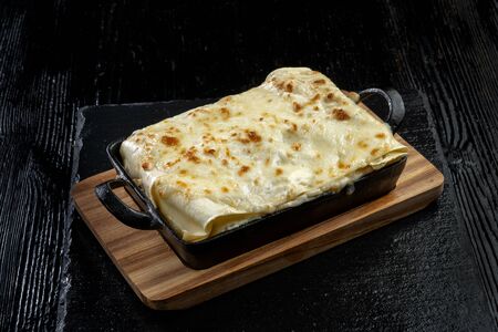 Piece of tasty hot lasagna. Traditional italian lasagna on a cast iron pan.の写真素材