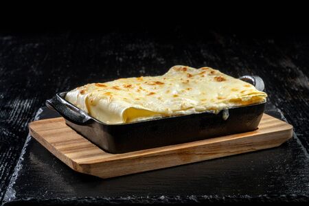 Piece of tasty hot lasagna. Traditional italian lasagna on a cast iron pan.の写真素材