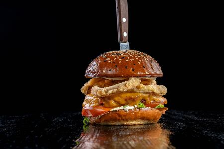 Gourmet craft bacon cheeseburger with tomatoes and onion rings.の写真素材