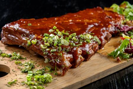Pork ribs with sauce laid out on a wooden board.の写真素材