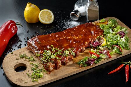 Pork ribs with sauce laid out on a wooden board.の写真素材