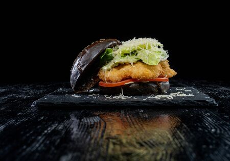 Fresh tasty chicken burger on a black lacquered table. Black bunの写真素材