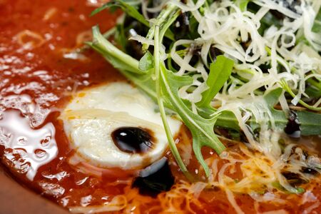 Tomato soup with arugula and grated cheese.の写真素材
