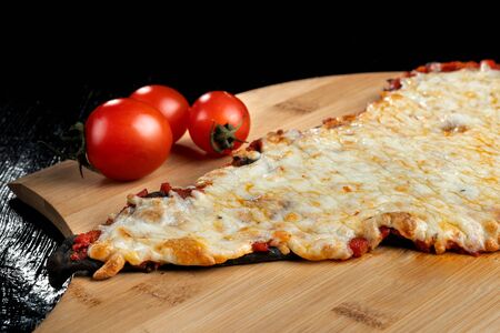 A slice of pizza from black dough lying on a wooden board.の写真素材