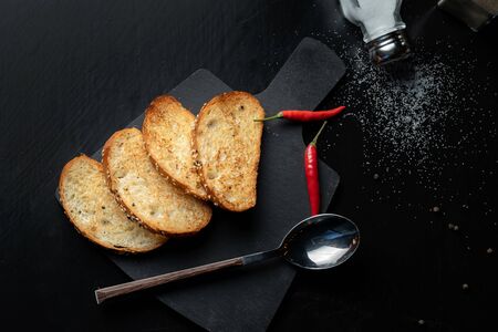 Toast the bread on a black slate, next is red pepper.の写真素材