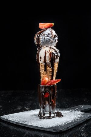 A horn of blueberry ice cream garnished with strawberries sprinkled with icing sugar.の写真素材