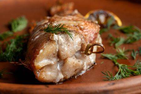 Grilled sea bass on a beautiful clay plate.の写真素材