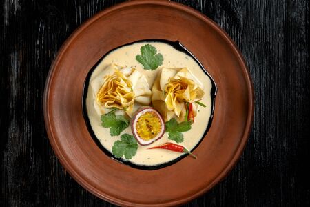 Pancakes stuffed with soyce and hot pepper. With delicious granadilla. On a beautiful clay plate, Top view.の写真素材