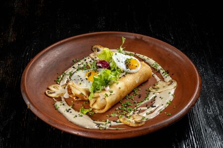 Rolled pancakes on top lies scrambled eggs. Beautiful clay plate. Diagonal view.の写真素材