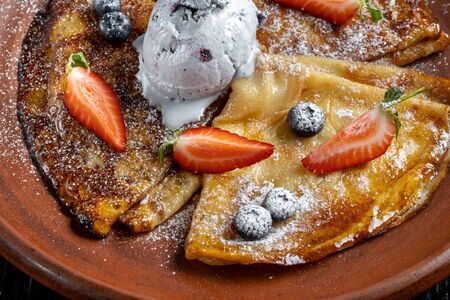 Pancakes with ice cream, with blueberries and strawberries, sprinkled with icing sugar. 45 view.