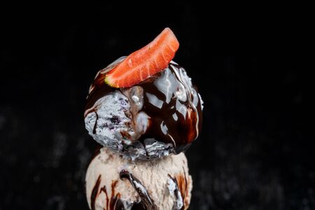 A horn of blueberry ice cream garnished with strawberries sprinkled with icing sugar.