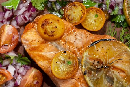 Grilled salmon and vegetables. Laid on a beautiful clay plate, sprinkled with onions, dill and tomatoes. Back light. Macro, top view.の写真素材