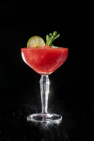 Strawberry daiquiri cocktail with lime, strawberry syrop, cherry and mint on black background.の写真素材