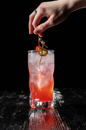 Alcoholic cocktail with juice garnished with cherry and jalapeno pepper planted for a long time.の写真素材