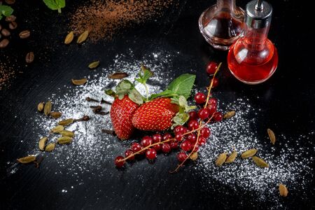 Strawberries with red currants sprinkled with powdered sugar. Laid out on black slate.の写真素材