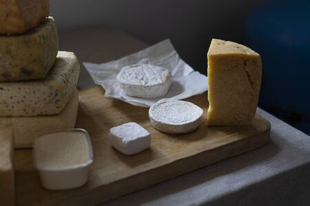 Cheese wheels produce for sale on the counter. Fresh cheese loaf selection, pile of many cheese mix....
