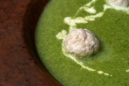 Green mashed soup with meatball in a rustic clay plate.の写真素材