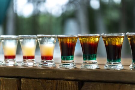 Shot drinks in row. Alcoholic shots on a wooden counter.