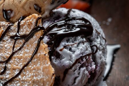 Plate with ice cream and waffles, poured with chocolate topping and decorated with strawberries.の写真素材