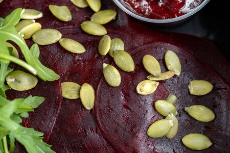 Salad, sliced beets with pumpkin seeds, close-up. With arugula salad. Many seeds are on beets.の写真素材