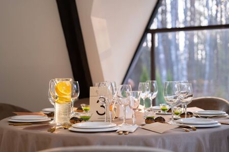 Chic and elegant, gold-plated cutlery and white plates, table setting with empty plates. Luxury restaurant, preparation for the celebration. Beautiful glasses and wine glassesの写真素材