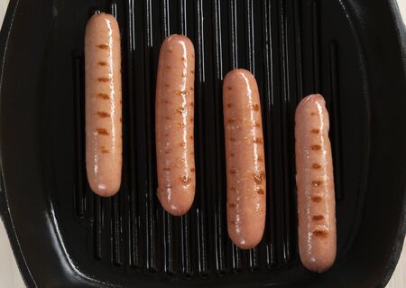 Fried sausages on a frying cast-iron pan, top view. Well done.の写真素材