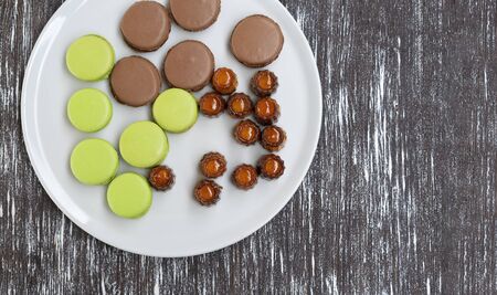Cookies of pasta, green and brown colors, as well as other sweets, are laid out on a plate.の写真素材