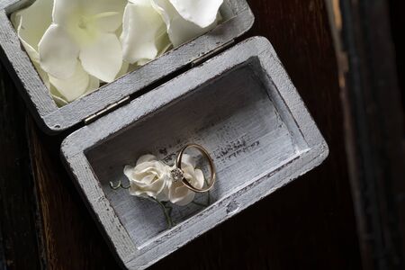 Engagement ring with a diamond, lies on a white polymer rose. In a beautiful wooden box.の写真素材
