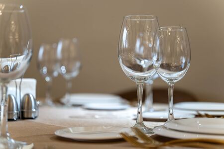 Chic and elegant, gold-plated cutlery and white plates, table setting with empty plates. Glasses in the light from the window-2.の写真素材