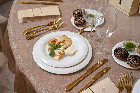 Chic and elegant, gold-plated cutlery and white plates. On the plate are several types of cheese. Luxury restaurant, preparation for the celebration.の写真素材