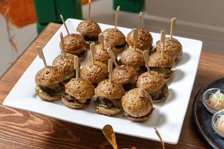 Mini burgers on white plate. With beautiful wooden skewers.の写真素材
