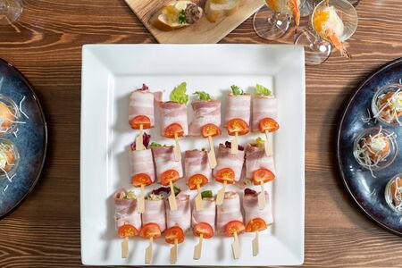 Bacon rolls stuffed with cheese and salad, a table with catering.の写真素材