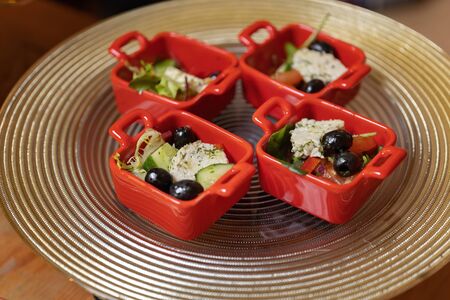 Organic caesar salad in red bowl with caesar dressing. Wooden table, luxury catering. Exposed on a beautiful steel dish.の写真素材