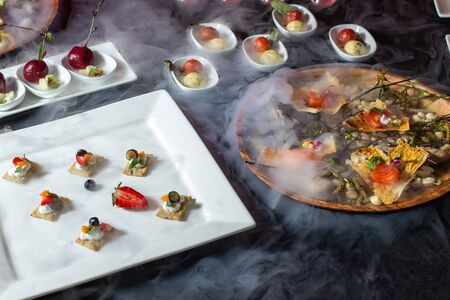 Catering, a table with dishes, a cup with liquid nitrogen, there is a beautiful smoke-2.の写真素材