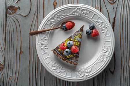 Slice of chocolate cake with nuts, decorated with berries, blueberries and raspberries.