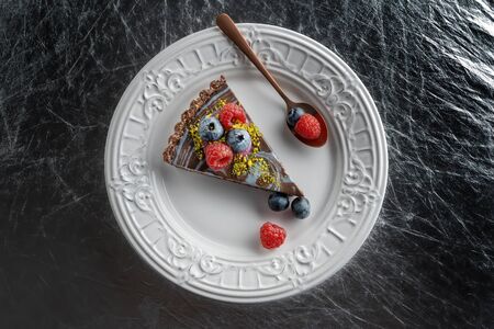 Slice of chocolate cake with nuts, decorated with berries, blueberries and raspberries.の写真素材
