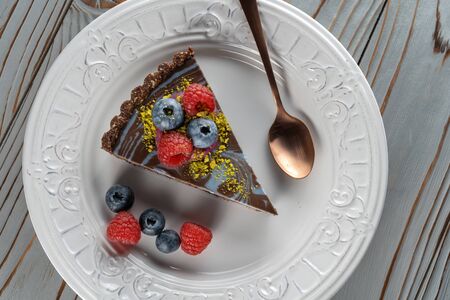 Slice of chocolate cake with nuts, decorated with berries, blueberries and raspberries.の写真素材