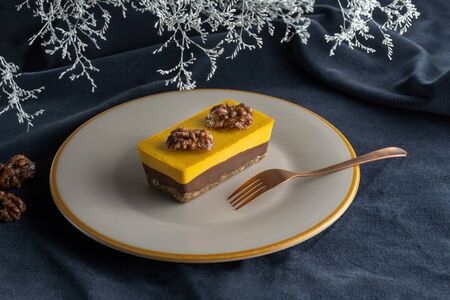 Homemade pumpkin pie with chocolate, and nuts. Decorated with walnuts. Laid on a plate, on the background of flowers.の写真素材