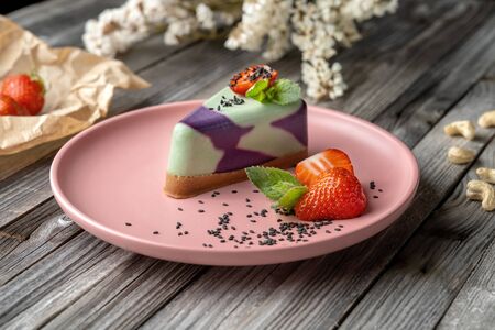 Blueberry cake, lemon, mint. Vegan, lactose free and sugar free. Laid on a pink plate, decorated with strawberries and sprinkled with black sesame seeds.の写真素材