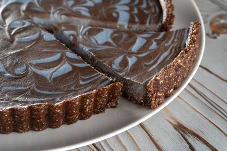Chocolate cake with nuts, laid on a plate. Beautifully cut piece. Wooden brushed background.の写真素材