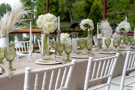Decorated wedding table, white peonies and feathers. Chiavari chairs are at the table. Wonderful summer day.の写真素材
