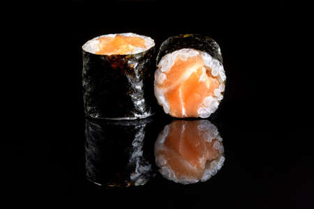 Rolls with salmon, rice, nori, fresh salmon. Black isolated background, beautiful reflection in a black mirror.の写真素材