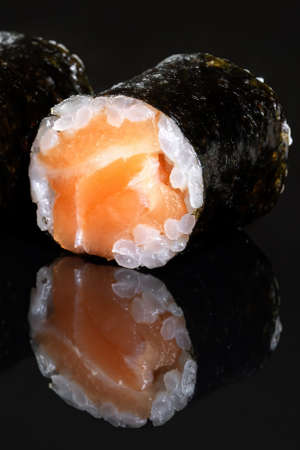 Rolls with salmon, rice, nori, fresh salmon. Black isolated background, beautiful reflection in a black mirror.の写真素材