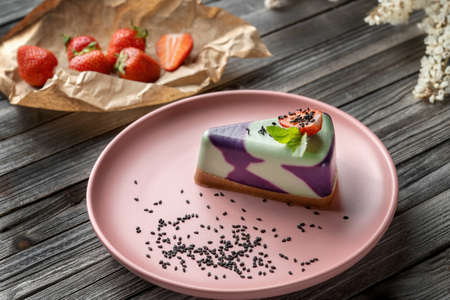 Blueberry cake, lemon, mint. Vegan, lactose free and sugar free. Laid on a pink plate, decorated with strawberries and sprinkled with black sesame seeds.の写真素材