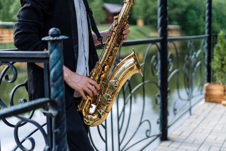 Man playing the saxophone, in the background is a beautiful lake.の写真素材